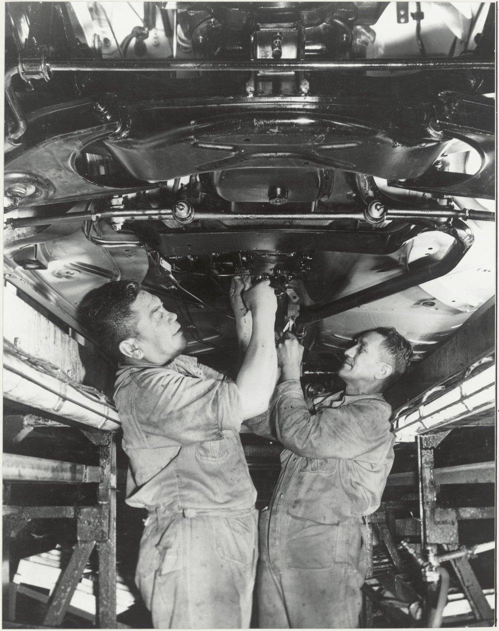 General Motors : workers underneath a car