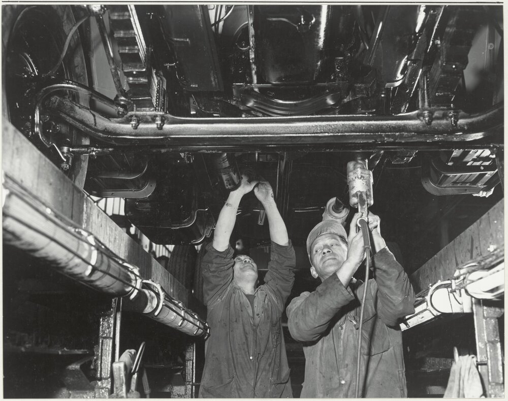General Motors: with workers working on the underside of a car