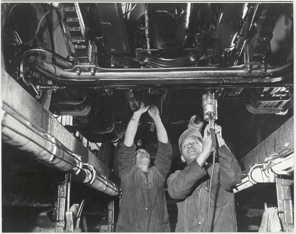 General Motors : workers underneath a car