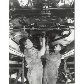 General Motors : workers underneath a car