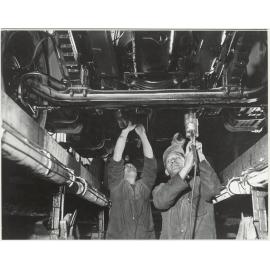 General Motors : workers underneath a car