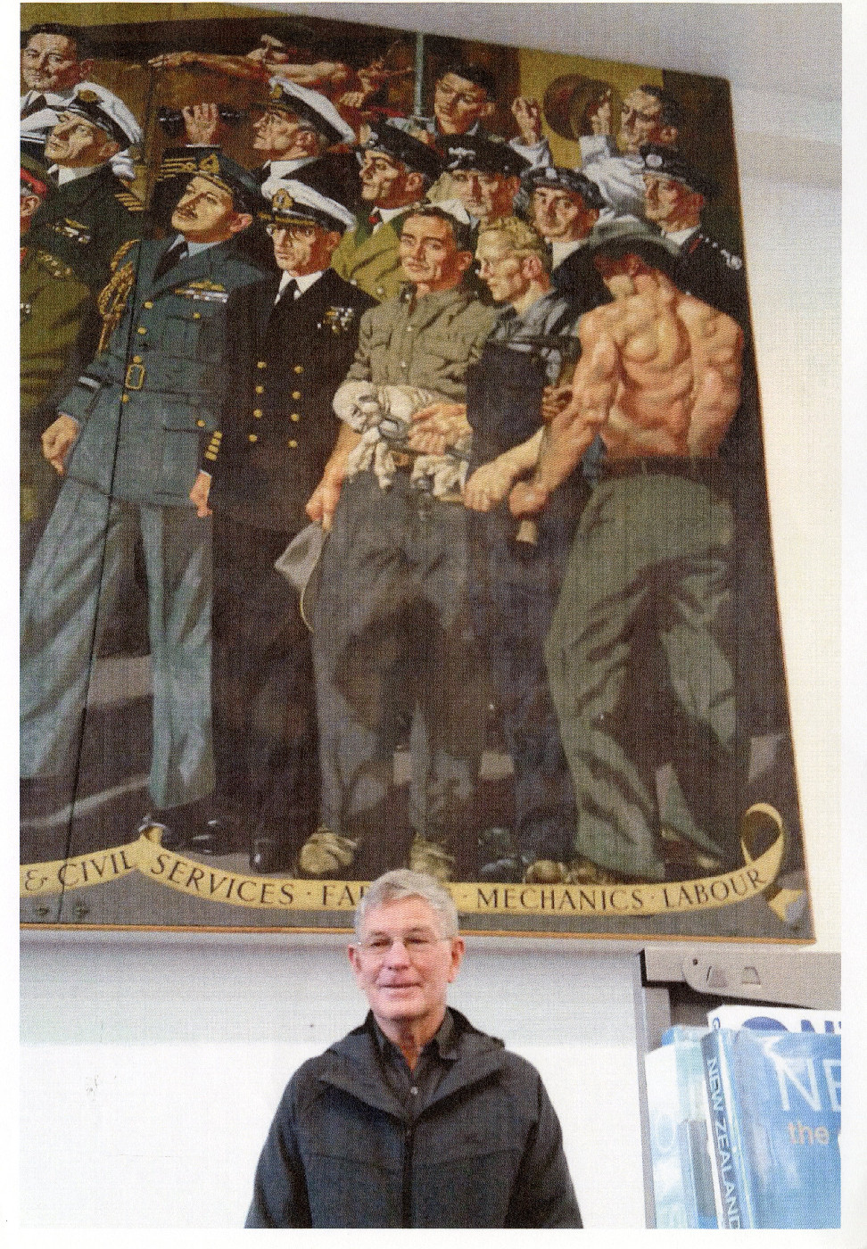 John Butt in July 2018 in front of the mural he modelled for in 1955. He is pictured in the back row, second from the right, the young plumber, no.43.